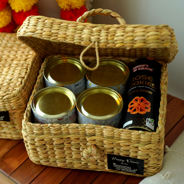 Woven Onam gift basket with canned goods and a bottle of olive oil on a wooden surface.
